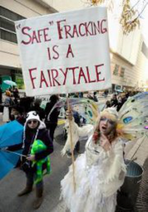 picutre of a protester dressedd as a fairy with wings and a sign "safe fracking is a fairy tale"